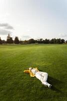 Young man relaxing lying down on a green meadow photo