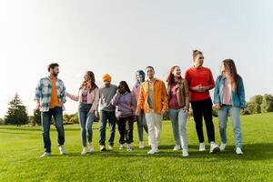 Group of diverse friends walking and talking together in park photo