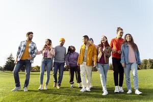 Group of friends walking and talking together in park photo