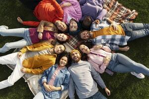 Diverse group of people lying in circle on grass smiling at camera photo