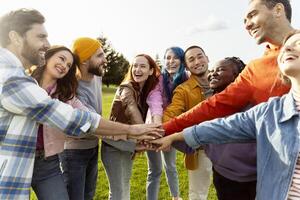 Diverse group of people joining hands in a circle outdoors photo
