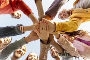 Group of people joining hands in a huddle smiling and bonding photo