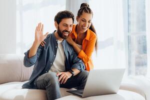 Portrait of happy, smiling Hispanic couple using laptop, waving hand having call photo