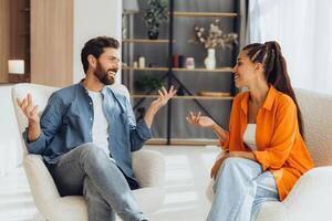 Smiling happy attractive middle aged couple talking, sitting together in comfortable chair gesturing photo