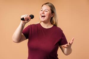 Happy plus size woman performing song in microphone heartily in studio photo