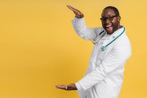 Happy African American doctor pointing at empty space by hands looking at camera photo