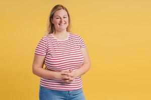 Happy young woman standing holding hands together looking at camera in studio photo