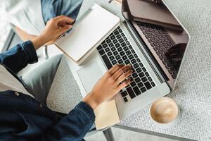 Freelancer working remotely from coworking space using laptop and notepad photo