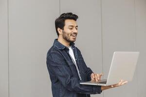 Smiling indian professional using laptop for remote work photo