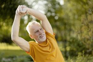 Senior man stretching arms in park, enjoying healthy lifestyle photo