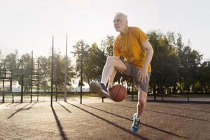Senior man playing basketball outdoors on a sunny day photo
