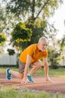 Senior man getting ready for running on track in park photo