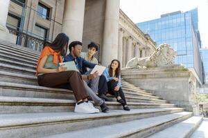 Students collaborating on university campus steps using digital tablet photo