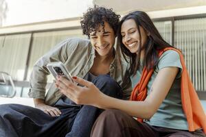 joven Pareja compartiendo un risa mientras mirando a teléfono inteligente foto