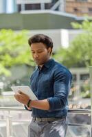 Young businessman standing in the city using a tablet computer photo