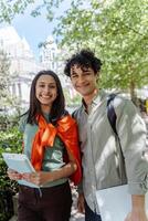 Two smiling students walking outside with books and technology photo