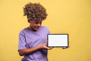 Smiling African American boy holding digital tablet with empty, white screen mockup photo