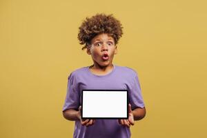 Portrait of excited African American boy holding digital tablet with empty, white screen mockup photo