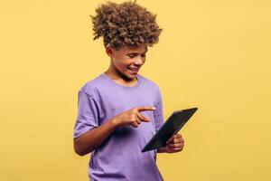 Smiling, attractive African American boy with curly hair holding digital tablet, using mobile app photo