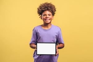 Attractive, smiling African American boy with curly hair holding digital tablet with empty screen photo