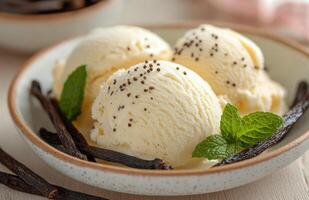 Creamy vanilla ice cream scoops with mint leaves and vanilla pods on a white plate photo
