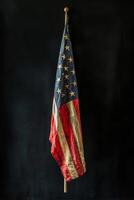Worn American flag displayed artistically against a dark background in a serene setting photo