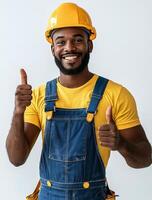 A young construction worker smiling and giving thumbs up while wearing a yellow hard hat photo