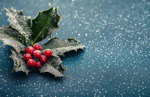 Frosted holly leaves with red berries placed on a shimmering blue background during winter photo