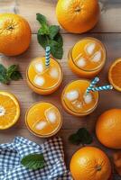 Refreshing orange drinks with ice and mint on a wooden table during a sunny day photo