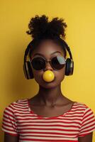 Young girl with headphones blowing bubble gum against a bright yellow background photo