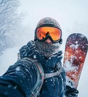Snowboarder takes a self portrait during a snowy day in the mountains while enjoying winter sports photo