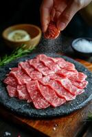 Preparing delicious thinly sliced beef with seasoning on a slate plate in a cozy kitchen setting photo