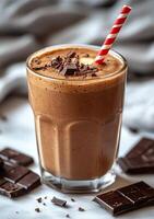 Decadent chocolate banana smoothie topped with chocolate pieces and a striped straw photo