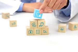 Hand holding a wooden block cube the top one with heart rate icon symbol. Medical and health concept. photo