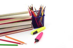 Crayon or colored pencils in box with side stack of books and school supplies on with background. Learning, study and office equipment concept. photo