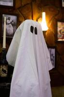 A friendly ghost appears by candlelight in an art-filled room adorned with vintage photographs photo