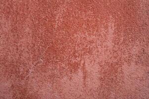 Vibrant textured wall with a warm reddish hue illuminated by soft light in an urban setting photo