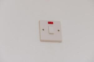 A Simple Wall-Mounted Light Switch With a Red Indicator Light in a Modern Interior Setting During Daylight photo