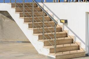 Staircase Leading to a Sunlit Terrace, Inviting Relaxation and Enjoyment by the Sea in a Bright Coastal Setting photo