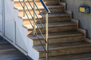 Modern Staircase With Polished Stone Steps and Sleek Railing in Natural Daylight at a Contemporary Home Entrance photo