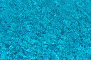 Luminous Turquoise Water Shimmering Under the Sun in a Tranquil Pool Oasis Amidst Vibrant Greenery on a Warm Summer Afternoon photo