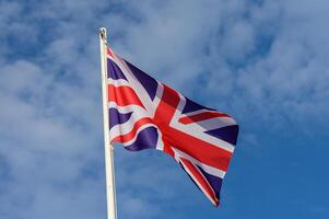 Union Jack flag waving against a bright blue sky during a sunny day in the United Kingdom showcasing national pride and identity photo