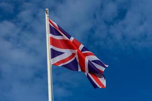 British flag waving proudly against a clear blue sky during a sunny day, symbolizing national pride and unity photo