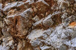 Natural rock formation with layers of gray and brown minerals at a geological site during daylight hours photo