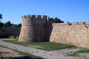 Ancient stone tower standing guard over lush greenery in a historic fortress at midday photo