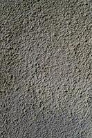 Textured surface of rough concrete wall in natural light creating an abstract design at midday photo