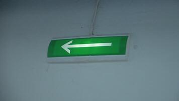 Glowing green arrow on wall. Clip. Arrow on green background lights up to indicate exit. Arrow of evacuation exit glows with green background on wall in building video