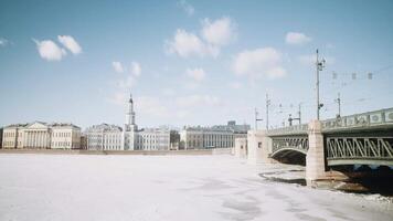 Beautiful view of ancient city with bridge and frozen river. Action. Ancient city with 18th century architecture on sunny winter day. Ancient city with frozen river on sunny day video