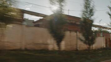 View fro the window of a moving car on the city street and industrial area. Stock footage. Green trees, low buildings. video