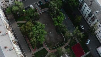 Person on playground in courtyard of modern houses. Stock footage. Top view of modern playground in residential complex. Modern landscape of residential area with playground video